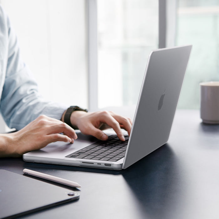 ACS11526 - MacBook Pro 16-inch Air Skin in Frost Clear showing a person typing on a MacBook with the Frost Clear case applied, placed on a desk in an office setting