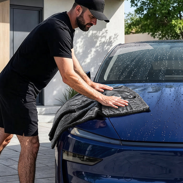 ACP11389 - Man using a gray Spigen microfiber towel to dry the hood of a wet blue car in a driveway